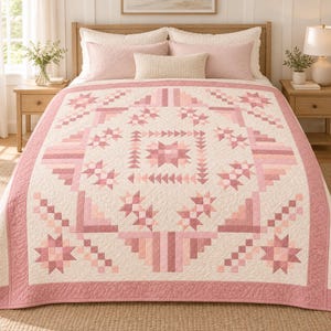 May include: A quilt featuring a geometric pattern in shades of pink and cream. The design includes star motifs, triangular shapes, and stepped blocks arranged in a symmetrical layout. The fabric has a quilted texture with visible stitching throughout.