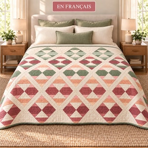 May include: A bed quilt featuring a geometric diamond pattern in shades of sage green, dusty rose, and cream. The quilt is layered over a bed with two large cream pillows, two sage green pillows, and one small sage green rectangular pillow.