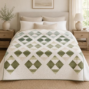 May include: A quilt featuring a repeating diamond pattern in shades of sage green, olive, and cream. The fabric has a subtle quilted texture throughout, with a white base color and a geometric design that creates a series of interconnected squares.