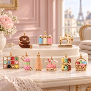 May include: A collection of gold-toned metal charms featuring sewing-themed designs including a brown measuring tape, three spools of thread, a sewing machine, a button box, yarn with needles, a thread cone, a pincushion, fabric rolls, and a basket.