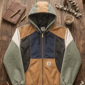 Puede incluir: Una chaqueta con capucha y cremallera de bloques de color en tonos beige, azul marino, verde oliva y crema. La prenda incluye un forro interior acolchado, una cremallera frontal completa, puños acanalados y una etiqueta de la marca Carhartt.