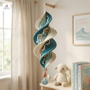 Peut inclure: Une décoration suspendue en crochet en forme de spirale, présentant des nuances dégradées de bleu sarcelle, de bleu et de crème. L'objet comporte de petits éléments en forme de coquillages et de coraux suspendus par une boucle.