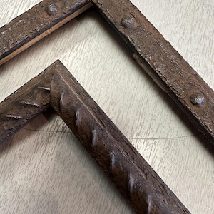 May include: Two rectangular picture frames with a dark brown, textured finish. The outer frame features raised, rounded stud details along its surface, while the inner frame displays a repeating diagonal, rope-like pattern along its edges.