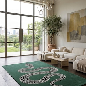 May include: A rectangular area rug featuring a deep green background with a large, stylised snake motif in black and white. The snake is depicted in a winding, S-shaped pattern across the centre of the rug, showcasing a detailed scale texture.