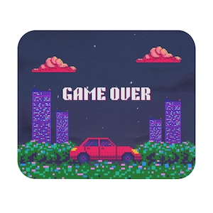 May include: A rectangular mouse pad featuring pixel art of a red car parked in a field of green and blue flowers. In the background, there are four tall buildings and two pink clouds against a dark purple sky. The text GAME OVER is centered.