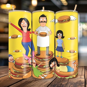 May include: A yellow cylindrical tumbler featuring a wrap-around graphic of the Belcher family from Bob's Burgers. The design includes characters standing on and interacting with large hamburgers, some with wings, against a bright yellow background.