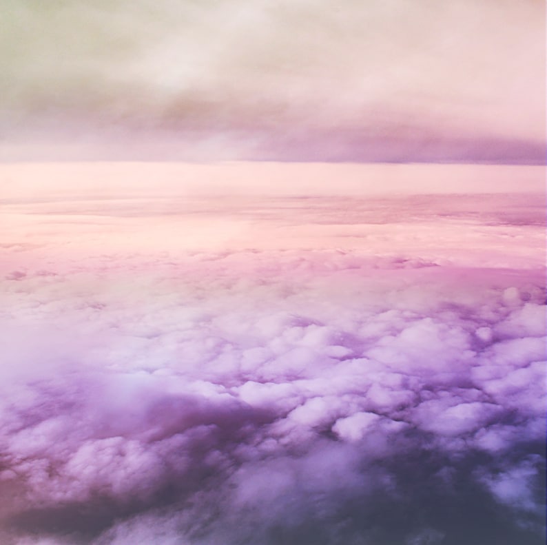 May include: A panoramic view of fluffy white clouds with a soft, pastel pink and purple gradient in the sky.
