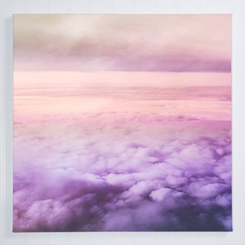May include: A photograph of a pink and purple sky with fluffy white clouds. The clouds are layered and create a gradient effect from pink to purple.