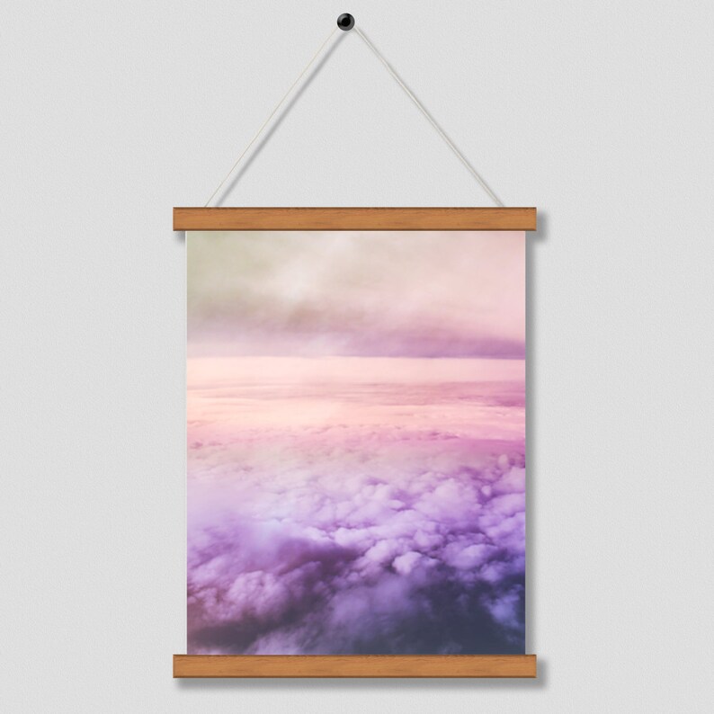 May include: A framed print of a pink and purple sky with clouds. The clouds are fluffy and white, and the sky is a soft pink and purple.