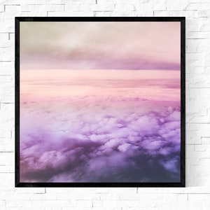 May include: A framed photograph of a pink and purple sky with clouds. The clouds are fluffy and white, and the sky is a soft pink and purple.