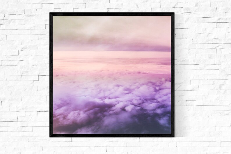 May include: A framed photograph of a pink and purple sky with clouds. The clouds are fluffy and white, and the sky is a soft pink and purple.