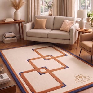 May include: A rectangular area rug featuring a cream-coloured base with a geometric pattern of interlocking orange squares and dark blue corner accents. The text AK CARPET STUDIO RUKS BRAND is printed in the bottom right corner of the rug.