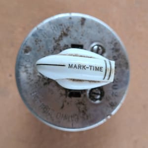 May include: Close-up of a silver and white electrical outlet with the text "MARK-TIME" on the white toggle switch.