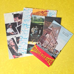 May include: A collection of vintage Grand Ole Opry memorabilia, including souvenir programs and promotional materials. The items feature images of country music performers and the Grand Ole Opry building, with text that reads "Souvenir Program" and "The Grand Ole Opry".