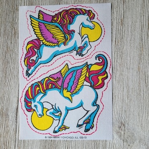 May include: Two vintage sticker sheets featuring colorful winged horses with pink, yellow, and blue accents. The stickers are on a white background with a pink dotted border. The text on the bottom of the sheet reads "© 1984 MARK 1 CHICAGO, ILL. ISS-19."