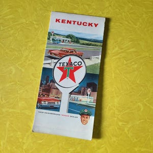 May include: A vintage Texaco road map for Kentucky. The map features a red star with a white "T" in the center and the words "Texaco" above it. The map also features a car driving on a road and a Texaco gas station.
