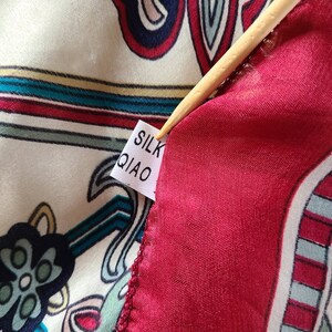 May include: Close-up of a red and white paisley patterned fabric with a white tag that reads "SILK QIAO".