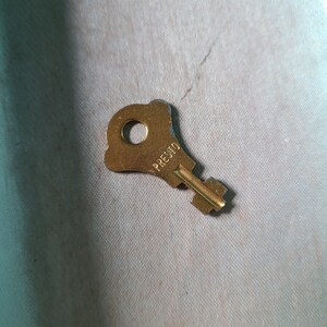 May include: A gold-colored key with a round hole in the handle and the word "PRESTO" engraved on the side.