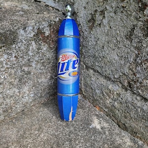 May include: A blue and silver Miller Lite beer tap handle with a silver top and a blue and white label that says "Miller Lite".
