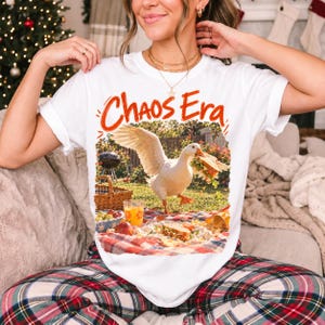 Goose stealing a sandwich from a picnic blanket, 90s film photo style, text "Chaos Era"