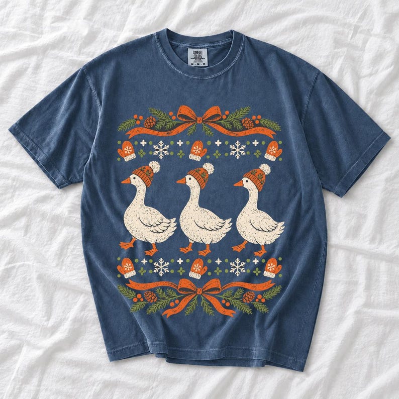 Three geese in pompom knit beanies with mittens, snowflakes and pine borders, retro winter t-shirt graphic