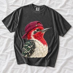 Colored-pencil red-headed woodpecker in side profile wearing a backwards corduroy cap, funny birder t-shirt graphic