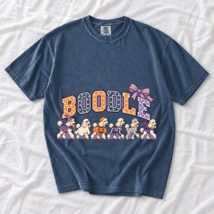 Six poodles in Halloween costumes walking under the arched word BOODLE, lavender and orange polka-dot varsity style