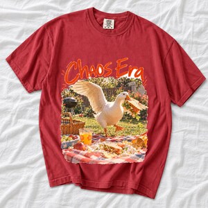 Goose stealing a sandwich from a picnic blanket, 90s film photo style, text "Chaos Era"