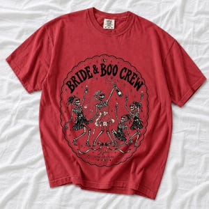 Skeleton bride popping champagne with cheering skeleton bridesmaids and the text Bride & Boo Crew