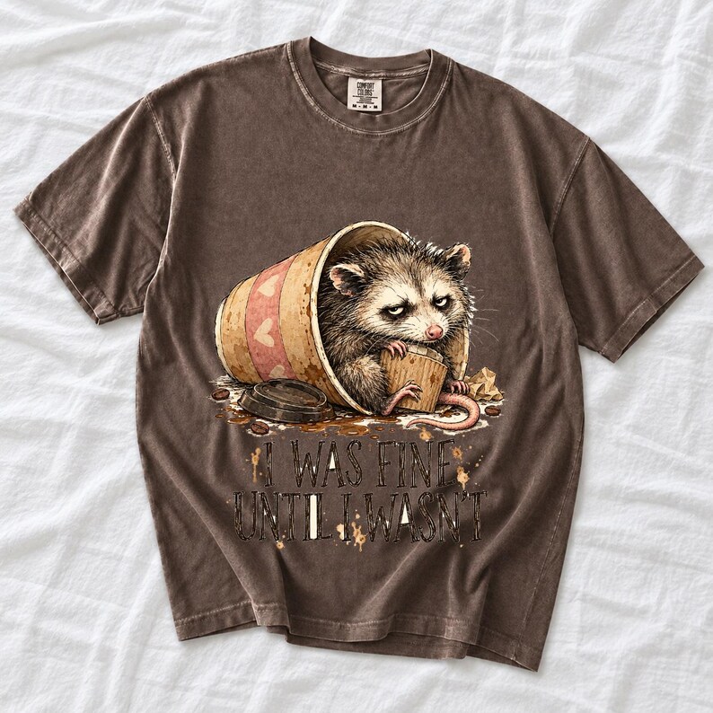 Tired opossum inside a tipped paper coffee cup with the text "I Was Fine Until I Wasn't", sepia watercolor sketch