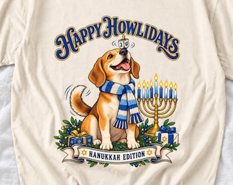 May include: A cream-coloured t-shirt featuring a graphic of a beagle wearing a blue and white striped scarf. The dog has a dreidel on its nose, sits beside a gold menorah, and is surrounded by gifts. Text reads Happy Howlidays and Hanukkah Edition.