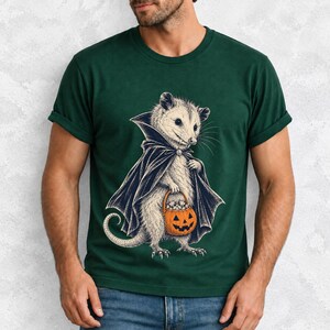 Etched pen illustration of an opossum in a vampire cape holding a candy pumpkin, bone white with orange accent