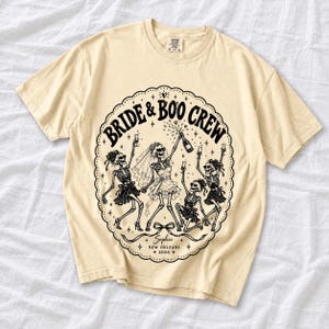 Skeleton bride popping champagne with cheering skeleton bridesmaids and the text Bride & Boo Crew