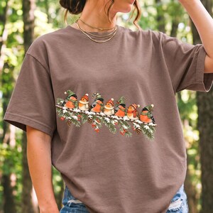 Watercolor bullfinches and robins in elf hats and scarves on a snowy pine branch