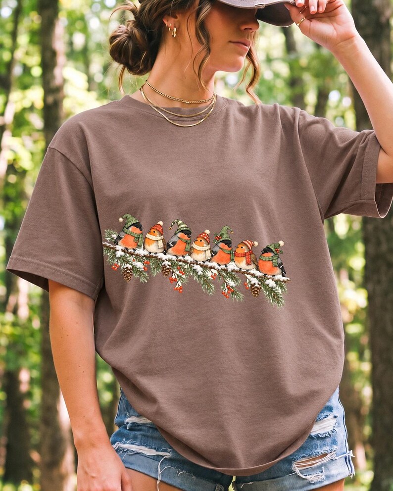 Watercolor bullfinches and robins in elf hats and scarves on a snowy pine branch