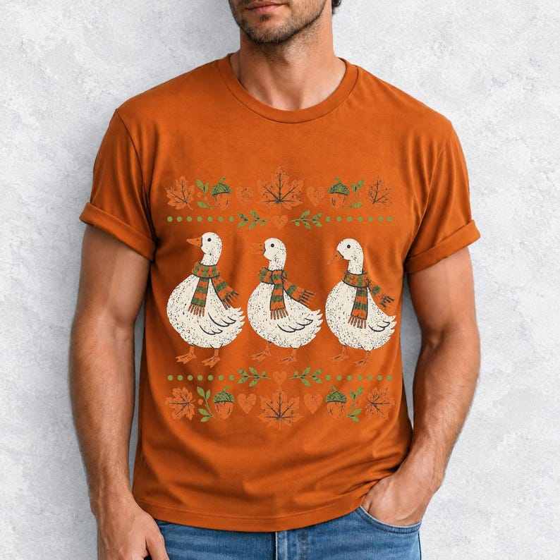 Three white ducks in striped scarves with acorn and maple leaf borders, retro screen print fall t-shirt art
