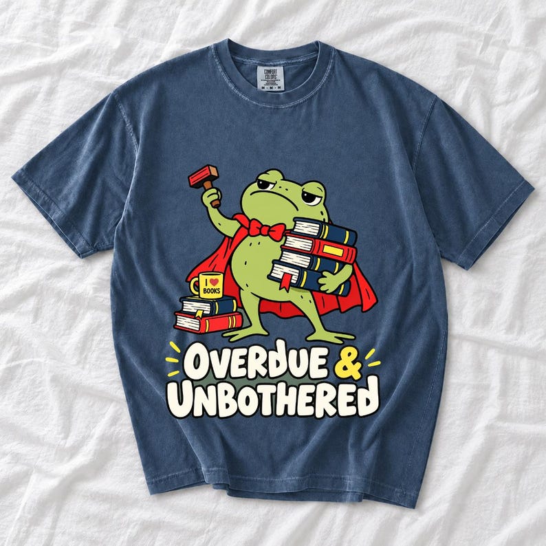 Grumpy cartoon frog librarian holding a stamp and a stack of books with the text Overdue & Unbothered