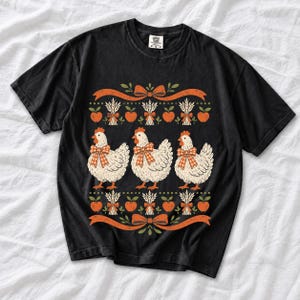 Three fluffy hens with gingham bows between apple and wheat borders, retro folk art fall t-shirt design
