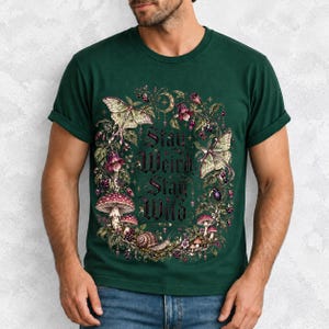 Victorian-style wreath of nightshade, luna moths and toadstools around the words "Stay Weird, Stay Wild"