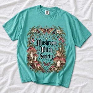 Blackletter text "Mushroom Witch Society" framed by fly agaric mushrooms, ferns and a toad on a mushroom cap