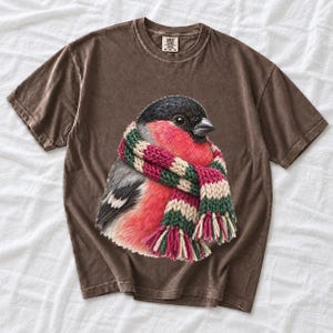Colored-pencil bullfinch bird wrapped in a chunky striped knit scarf, cozy winter birdwatcher t-shirt art
