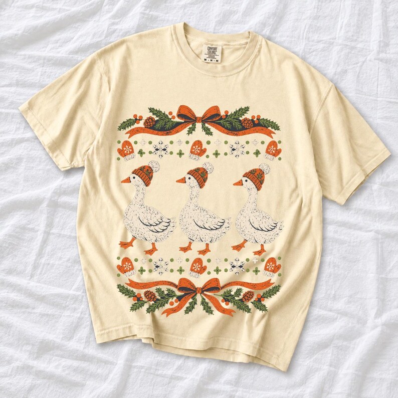 Three geese in pompom knit beanies with mittens, snowflakes and pine borders, retro winter t-shirt graphic