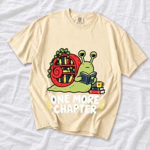 Cartoon snail reading a book with a bookshelf shell and the text One More Chapter