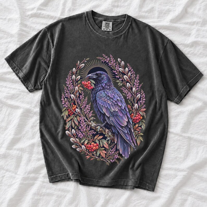 Raven holding a rowan berry inside an oval wreath of heather and catkins, painted cottagecore bird illustration