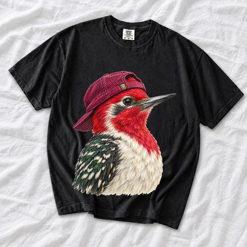 Colored-pencil red-headed woodpecker in side profile wearing a backwards corduroy cap, funny birder t-shirt graphic