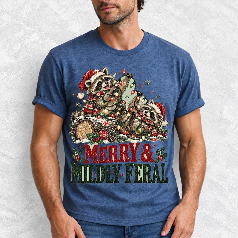 Two raccoons tangled in Christmas lights beside a log with the text Merry & Mildly Feral