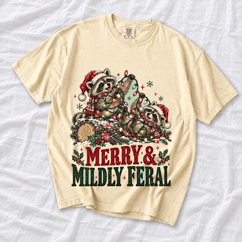 Two raccoons tangled in Christmas lights beside a log with the text Merry & Mildly Feral