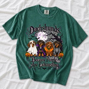 Four dachshunds in Halloween costumes under a spooky tree with text Dachshunds, Because People Are Exhausting