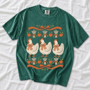 Three fluffy hens with gingham bows between apple and wheat borders, retro folk art fall t-shirt design