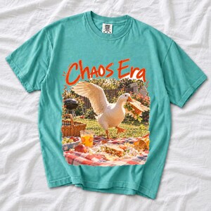 Goose stealing a sandwich from a picnic blanket, 90s film photo style, text "Chaos Era"